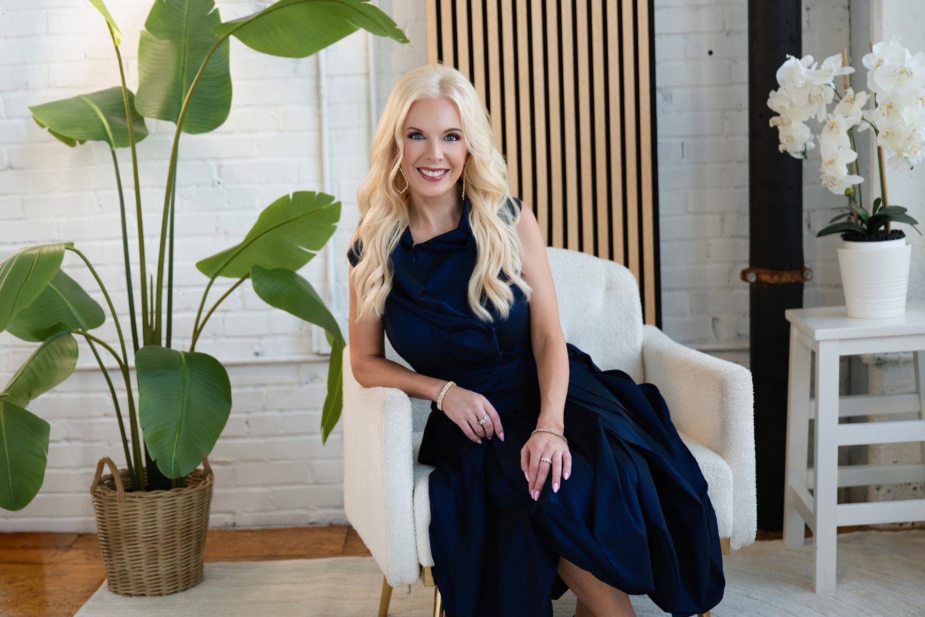 Stefani Seek seated in a navy dress on a cream armchair